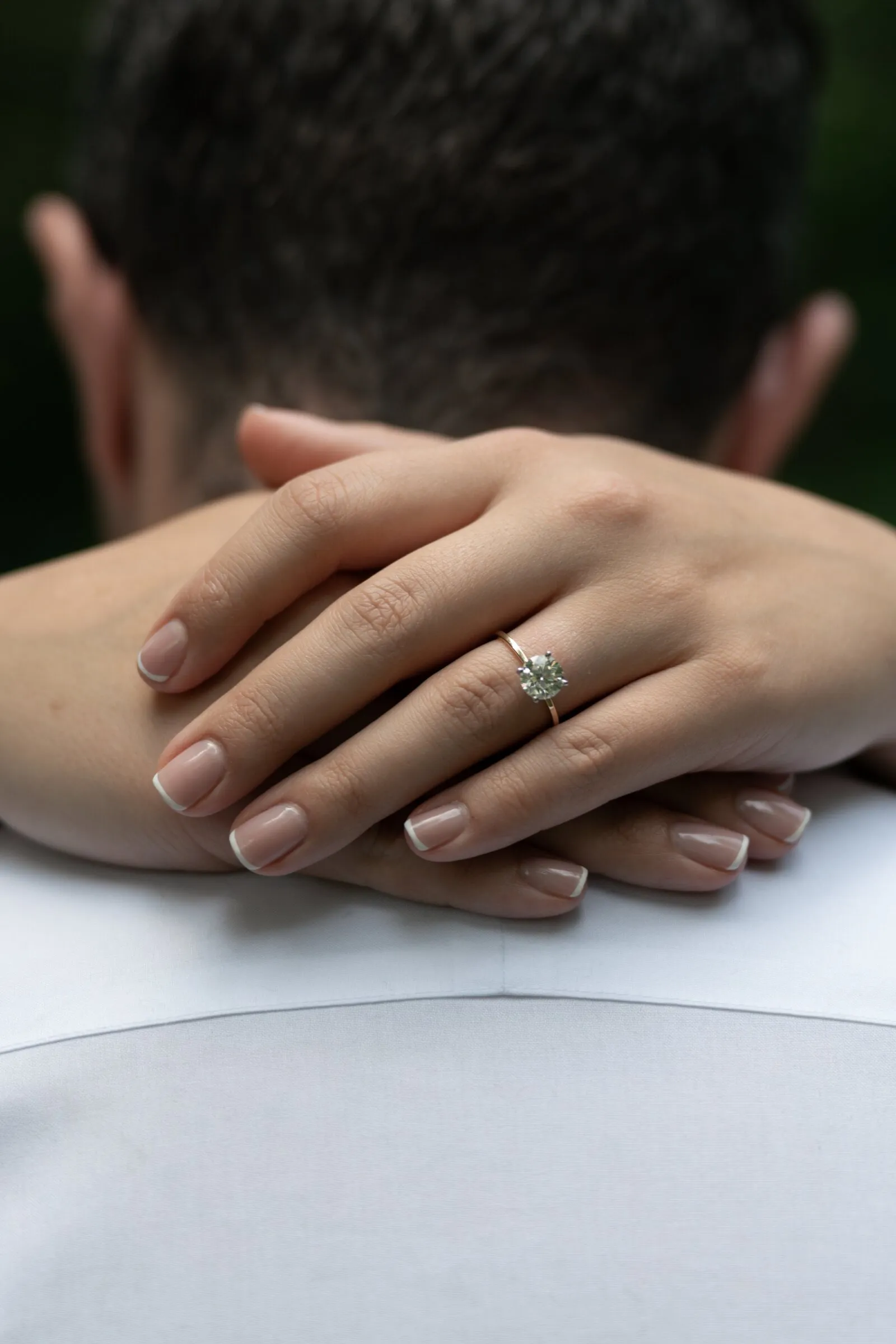 Close detail of Kayla's hands resting on Spencer's shoulder, her ring on her left hand