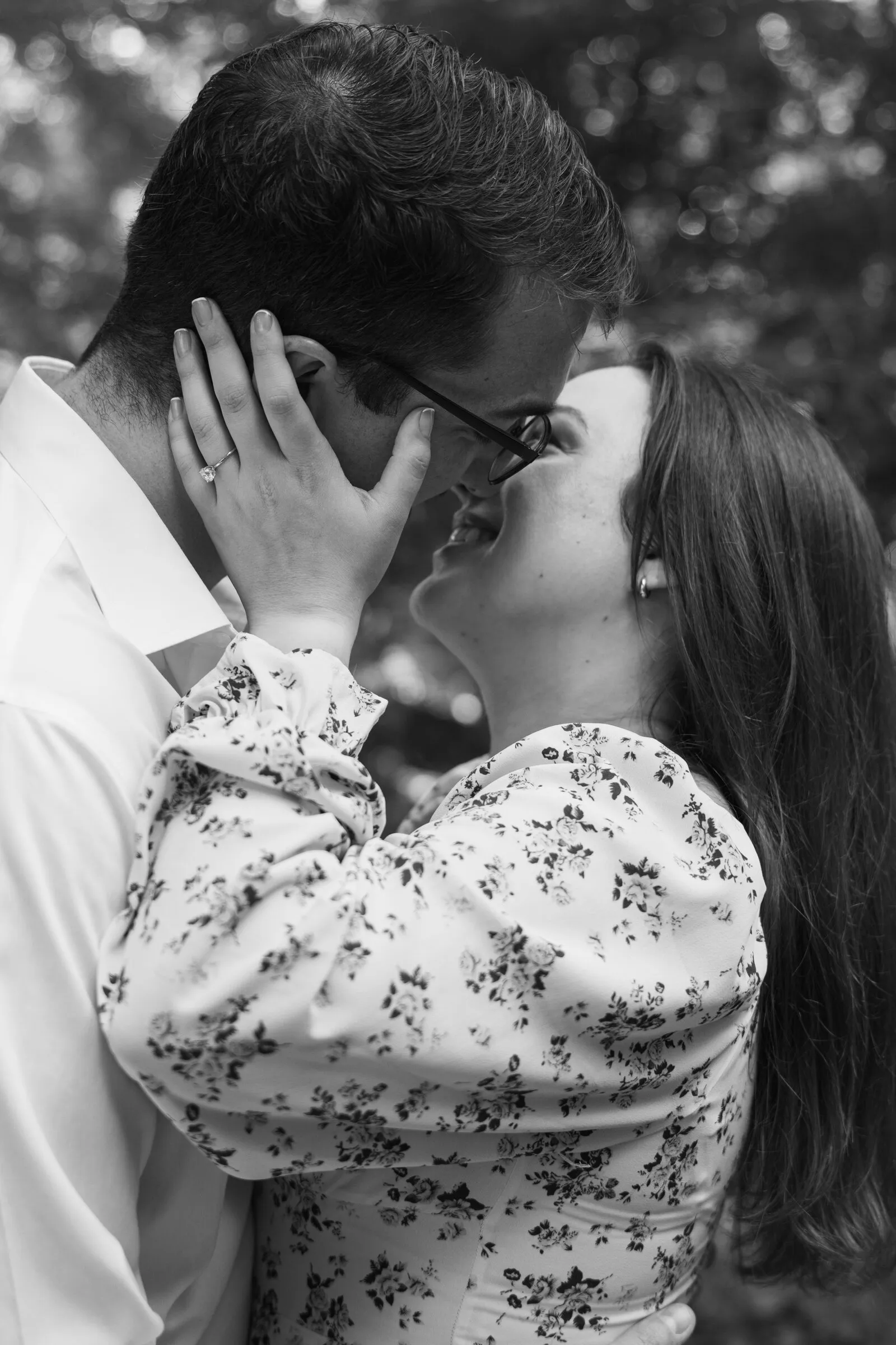Black and white photograph of Kayla holding Spencer's face for a kiss
