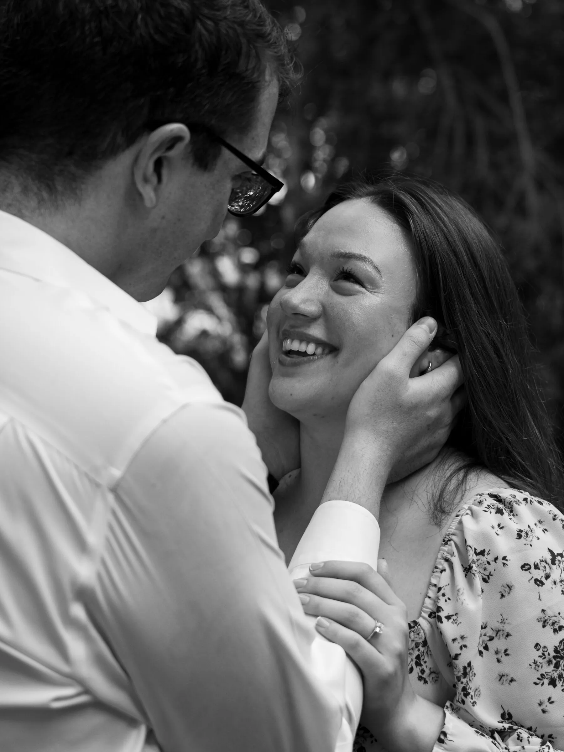 Black and white frame of Spencer cradling Kayla's face as she smiles up at him