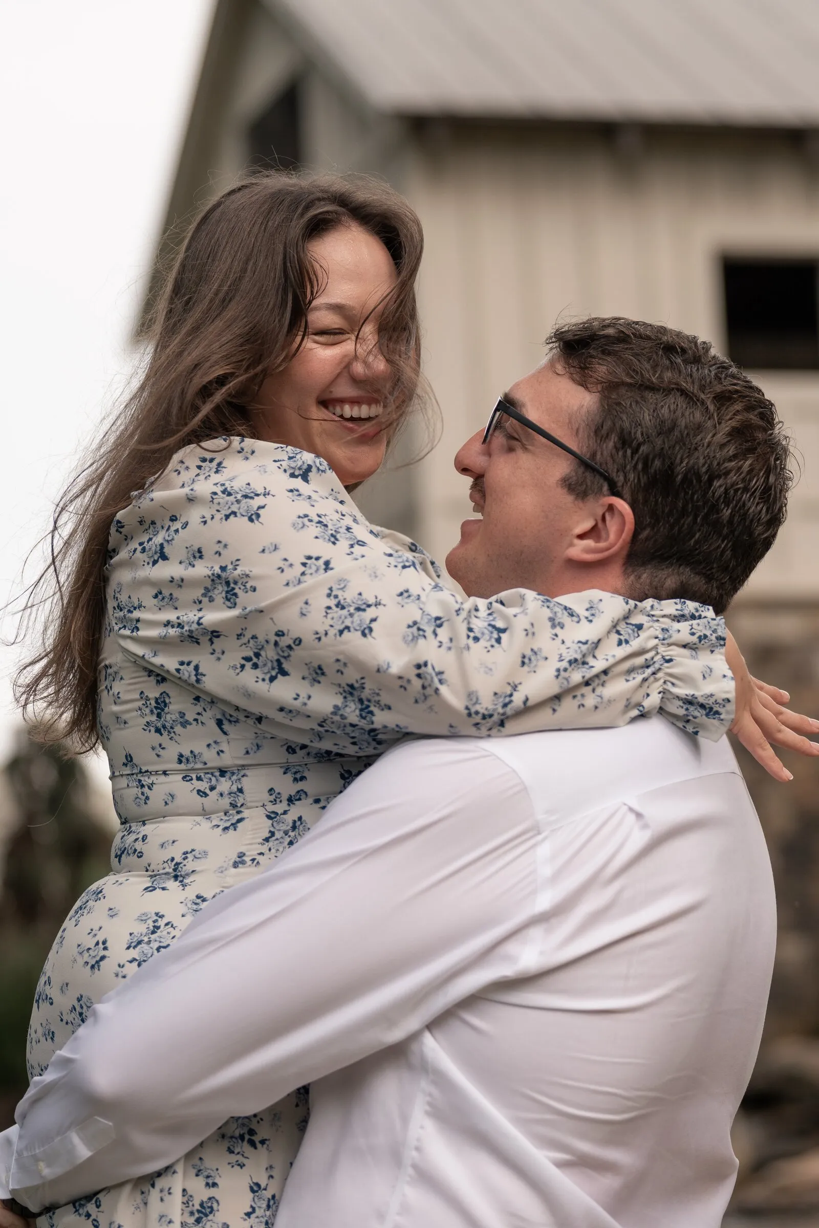 Kayla laughing, hair flying, as Spencer holds her up in his arms