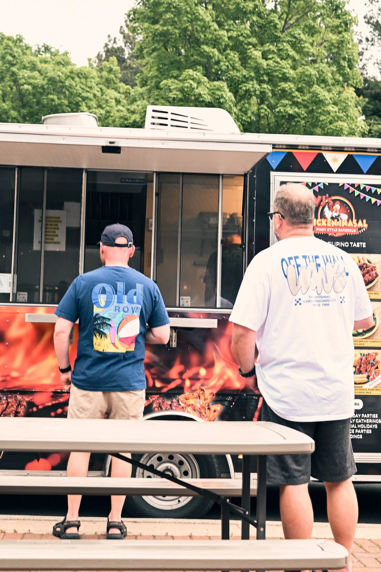 Two customers ordering at the window of the VJ's Chicken Inasal food truck
