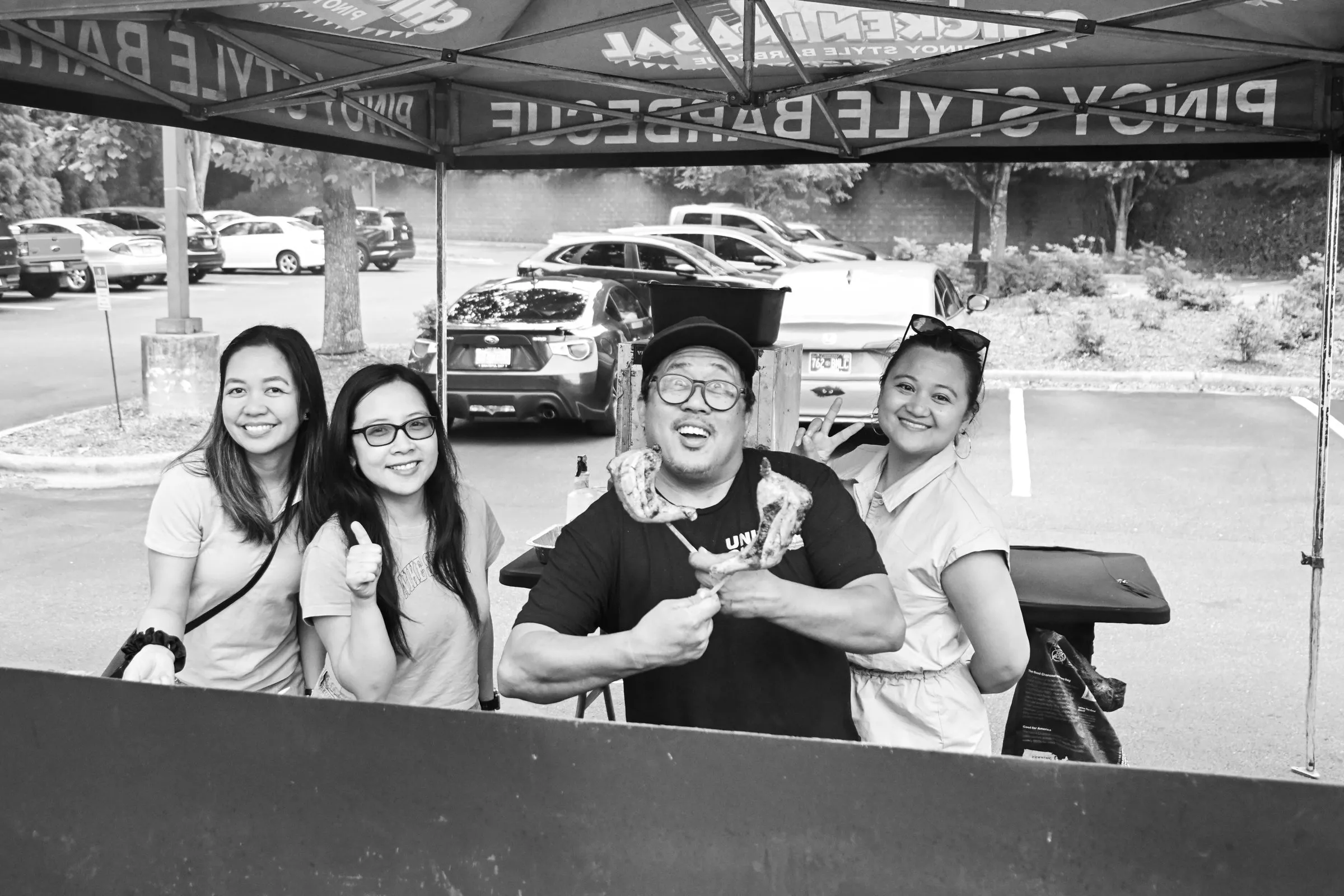 Black and white photograph of the VJ's Chicken Inasal crew posing behind the grill under the tent
