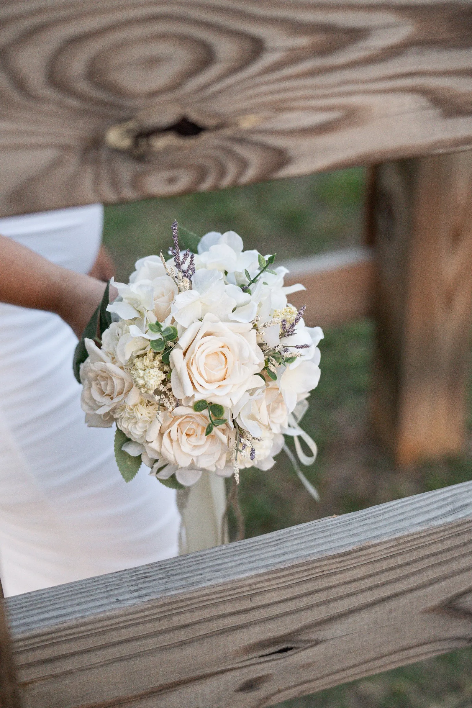 Winnie's bouquet framed between the rails of a wooden fence, her white gown just in view beside it