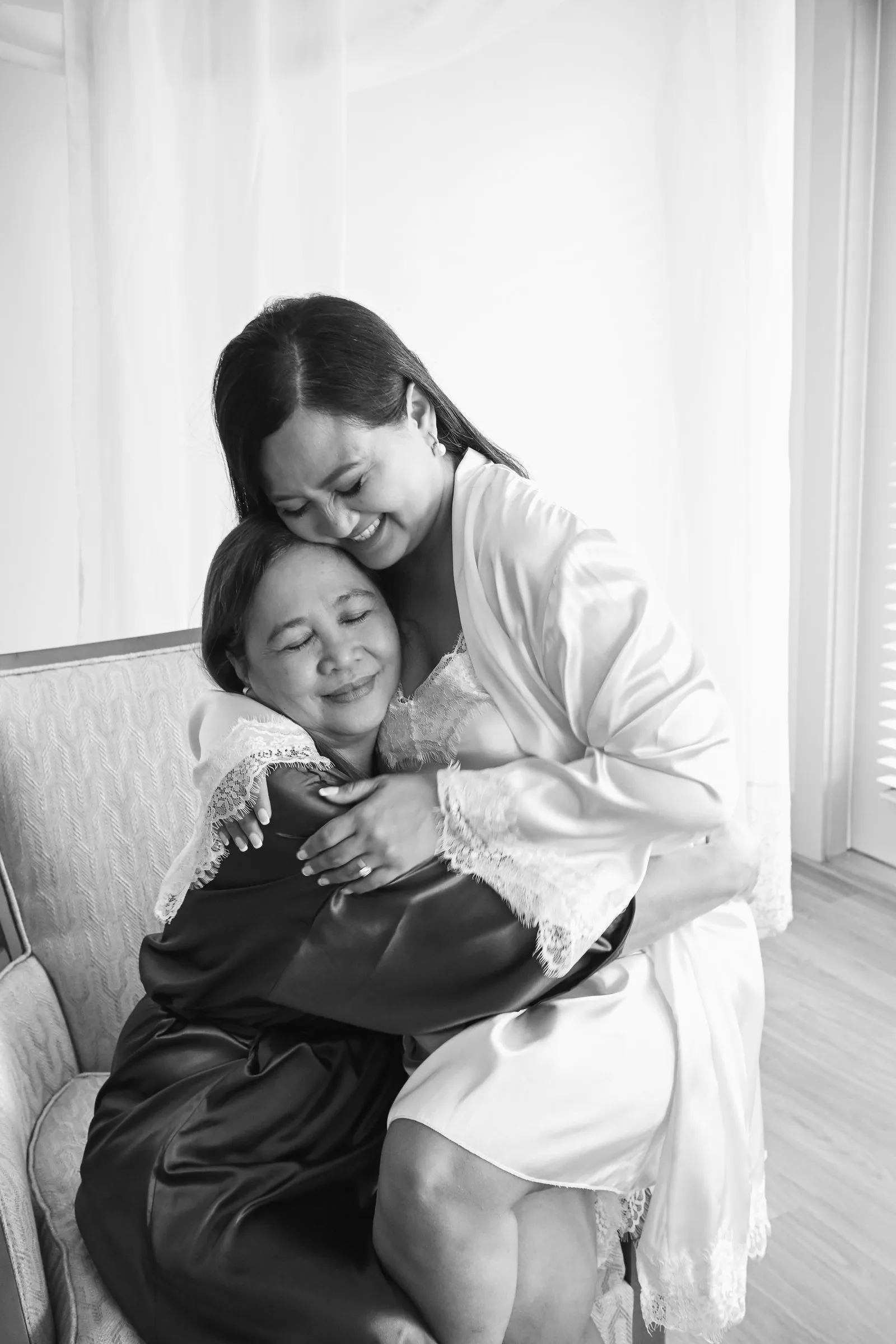 Black and white photograph of Winnie wrapping her mom in a tight hug, her mom's eyes closed